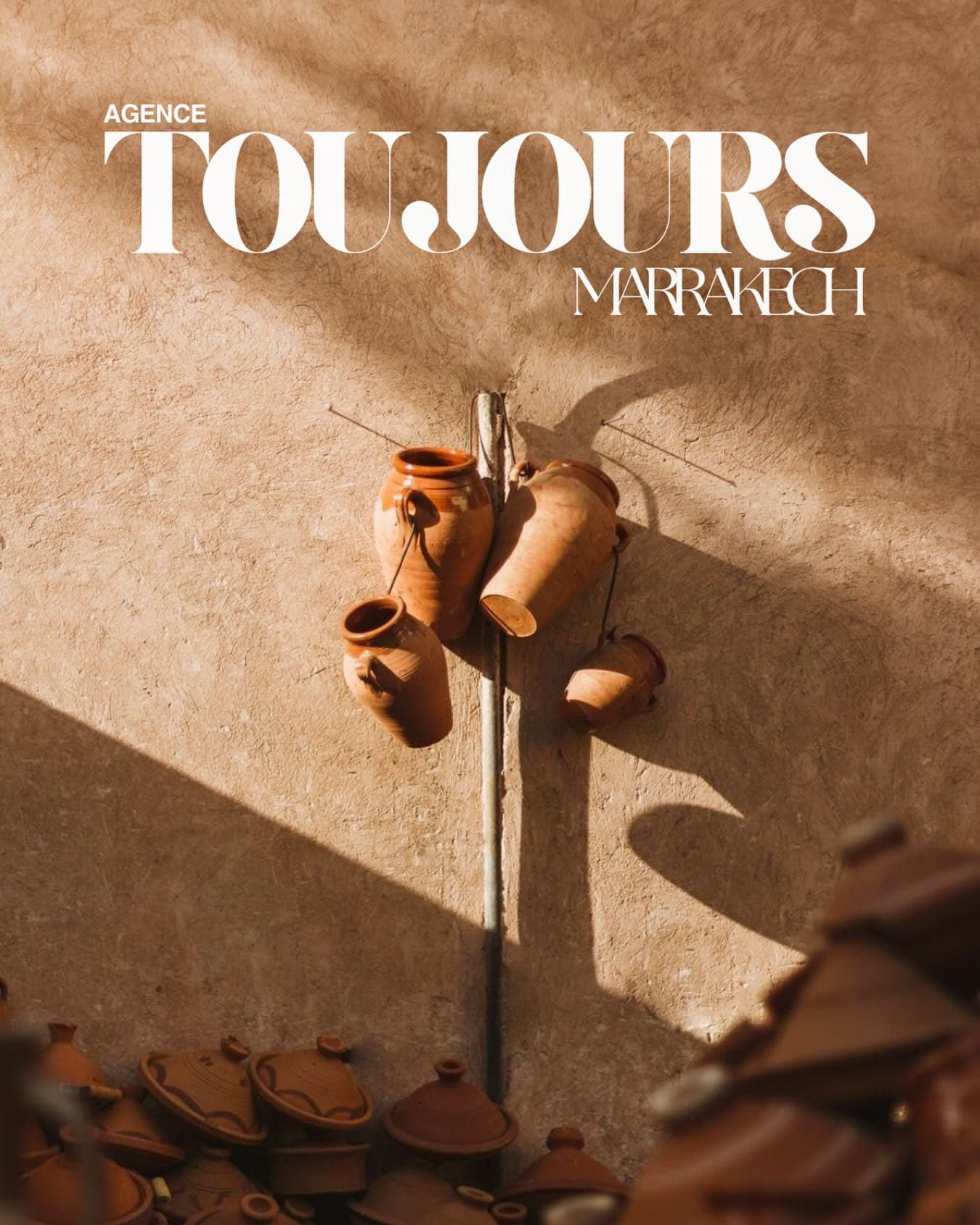 Clay pots hanging on a sunlit wall above rows of tagines